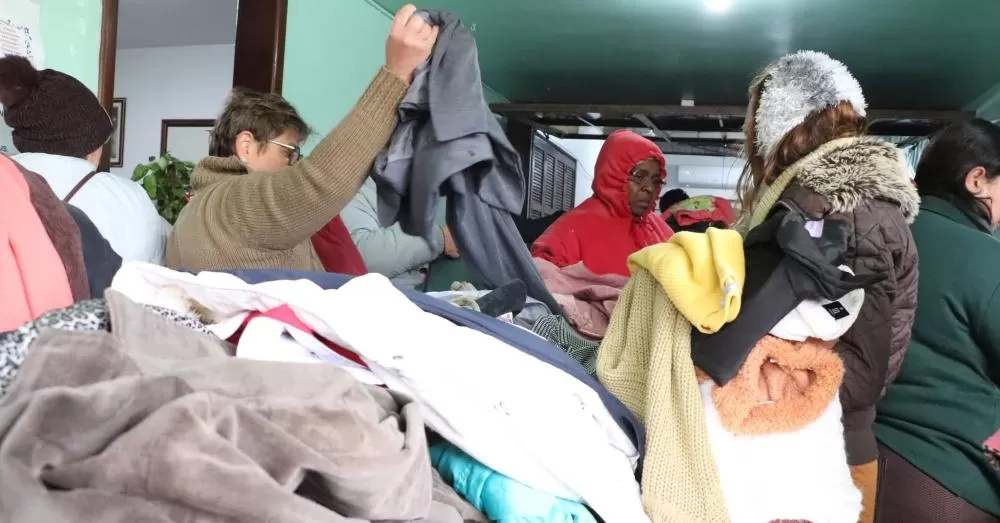 Beneficiários escolhem cobertores e roupas no Centro de Distribuição durante entrega da 17ª Campanha do Agasalho.