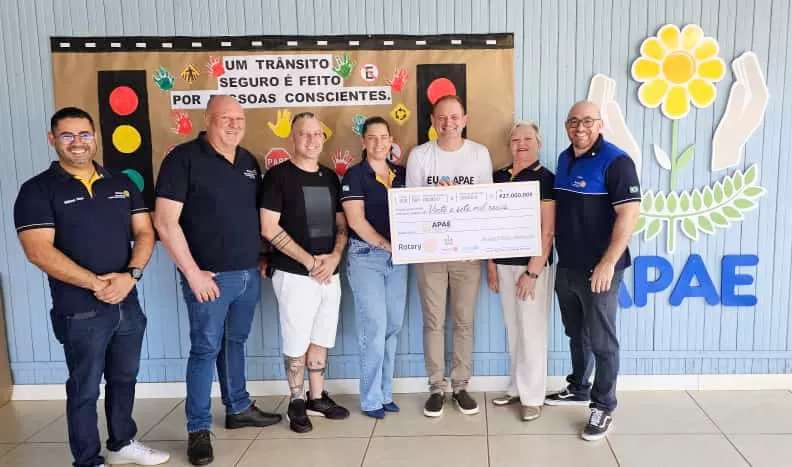 Entrega simbólica do cheque de R$ 27 mil da Família Rotária à APAE, durante a ExpoRondon 2025. {Foto: Divulgação)