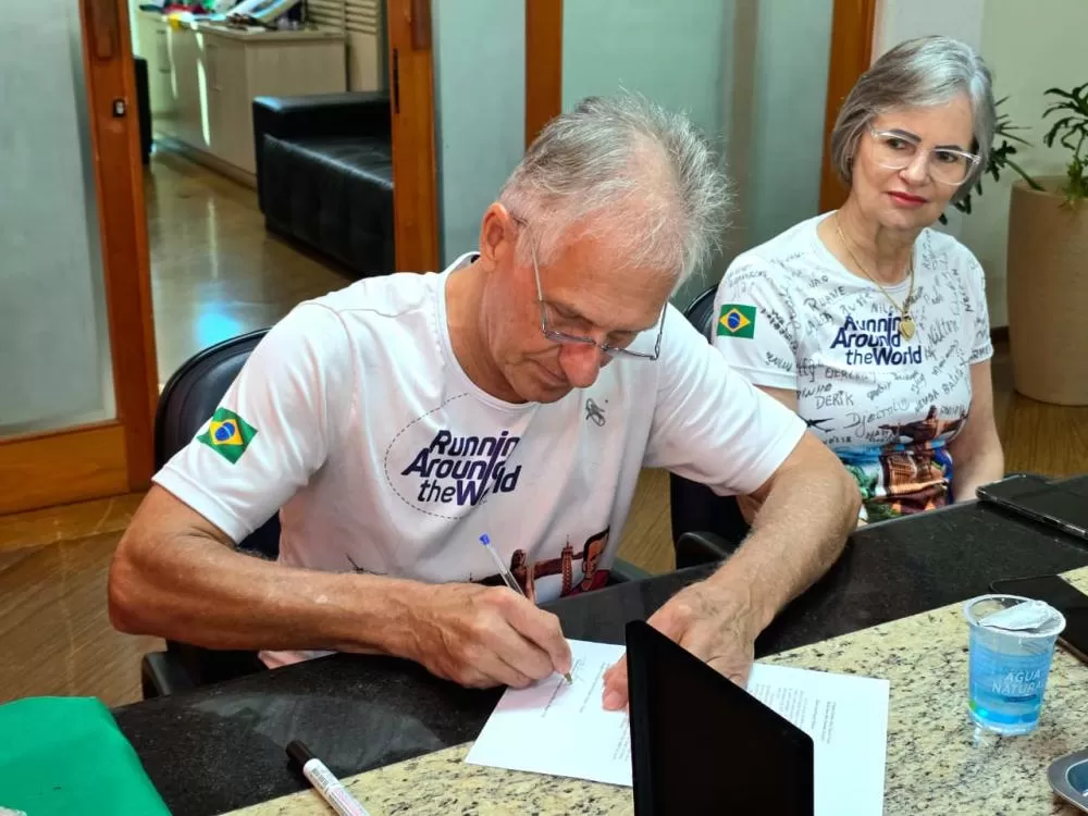 Nilton e esposa Dorli, ele assinando a Carta Institucional que o município envia ao prefeito da cidade italiana sede da competição. (Foto: Diculgação)